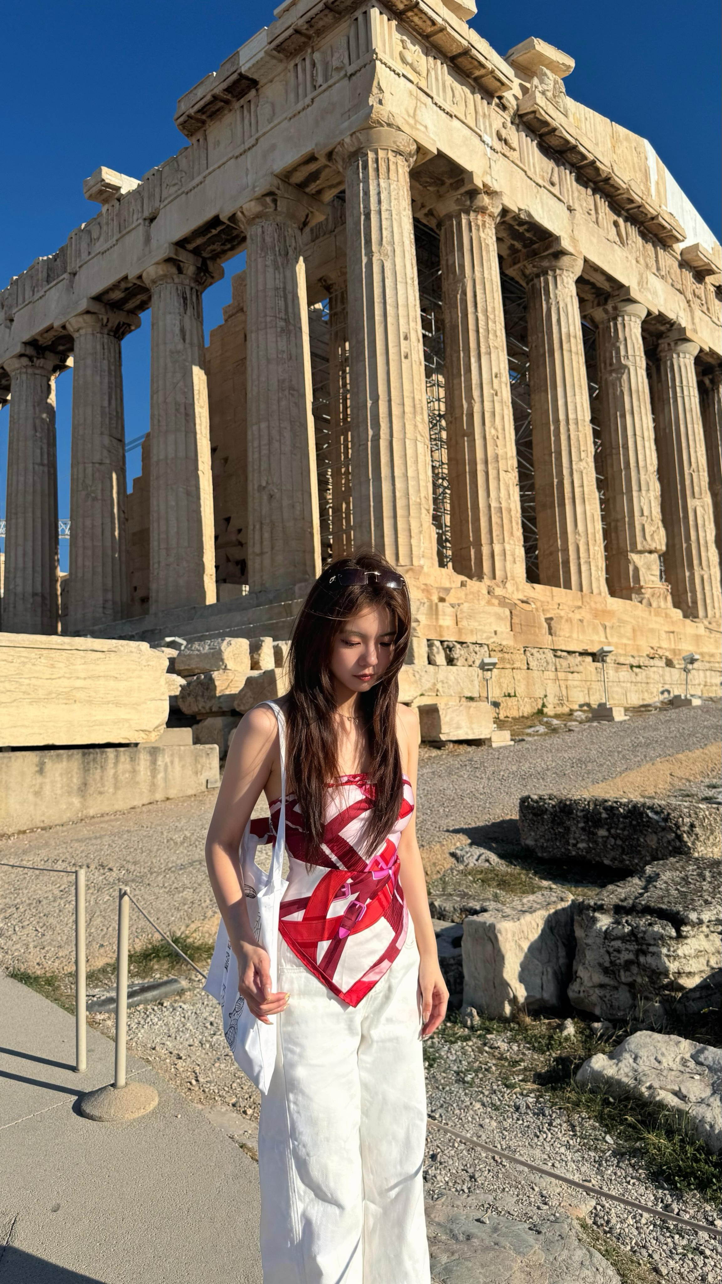 Shan in front of a classical stone temple under a blue sky